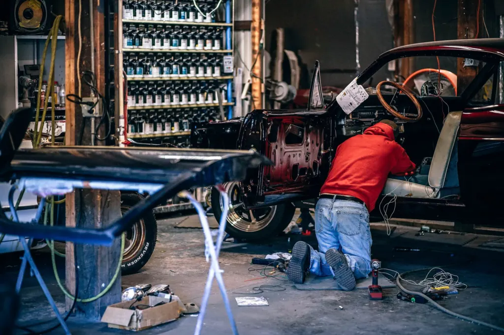 Technician working on a car body inside a vehicle repair workshop