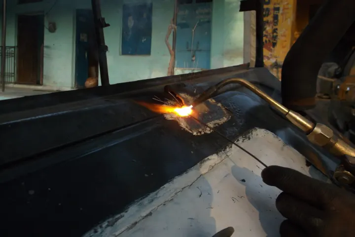Technician heating and shaping a metal car body panel